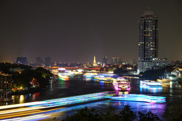 View of Bangkok, Thailand at night, showing the Chao Phraya River and boats. Taken on 22 Dec 2023.