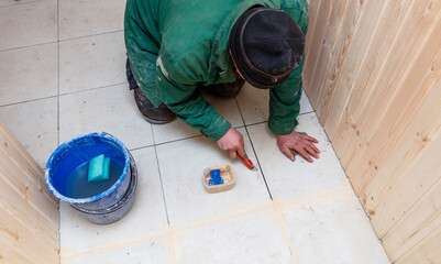 A man is painting a floor with a blue bucket