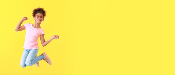 Jumping African-American girl in jeans on color background