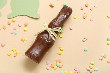 Chocolate Easter bunny and sprinkles on beige background