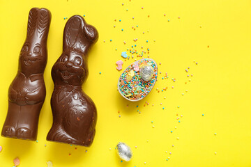 Chocolate Easter egg with sprinkles and bunnies on yellow background