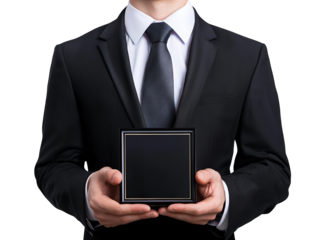 A man in a formal suit holds a small, sleek black box in both hands, presenting it with an air of anticipation.