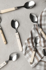 Different silver spoons and napkin on grey background