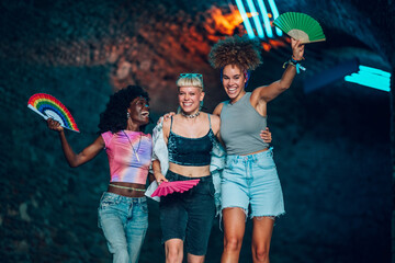 Happy friends enjoying music festival with colorful hand fans