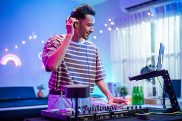 Asian young man artist DJ mixing and scratching music mixer controller. 