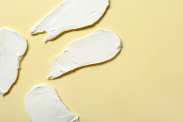 Samples of cosmetic cream on yellow background