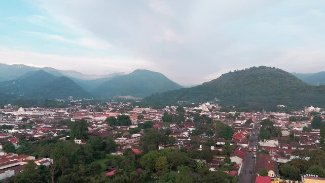 Paisaje urbano de pueblo colonial con casas de techos rojos rodeado de monta&ntilde;a, Antigua Guatemala, Guatemala
