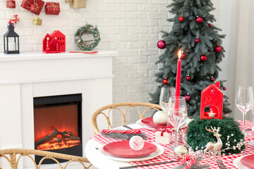 Festive Christmas dinner table setting with ornaments and fir branches in light dining room