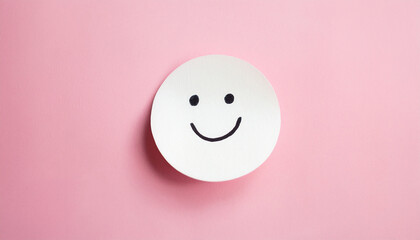 White sticky paper note with drawn happy emoji face on pink background. Emotion, mental state