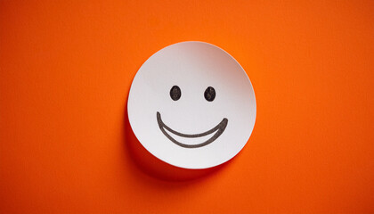 White sticky paper note with drawn happy emoji face on orange background. Emotion, mental state
