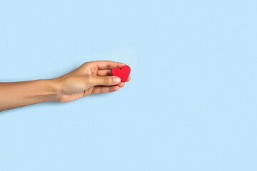 hand holding a red heart on a blue background