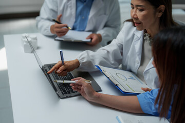 Medical team analyzing data on laptop with charts and medicine bottles