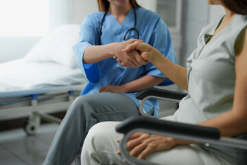 Obraz premium Doctor shaking hands with senior patient in wheelchair at hospital