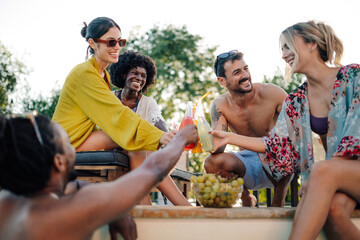 Friends toasting drinks at a pool party celebrating summer