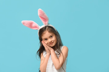 Cute little girl in bunny ears on blue background