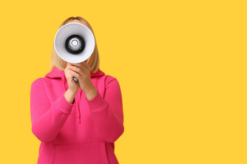 Fototapeta premium Mature woman with megaphone on yellow background