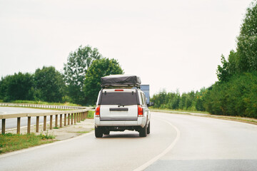 Obraz premium SUV with roof sleeping tent in motion on the highway