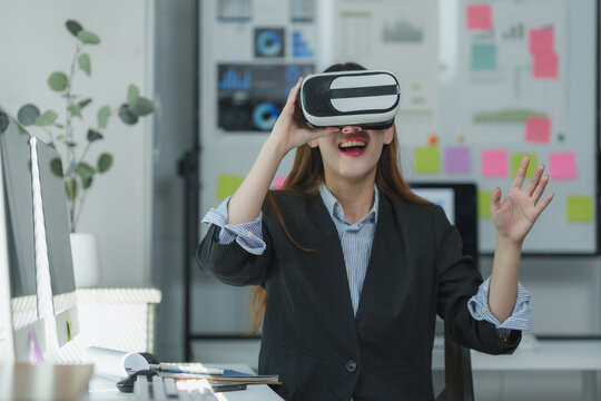 Businesswoman wearing vr headset is enjoying virtual reality experience in office - Powered by Adobe