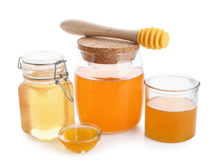 Glass, jars and bowl of sweet honey with dipper on white background