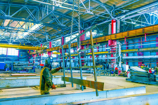 Steel frame in selective focus in the welding shop of a metalworking plant. Production of metal profiles. Factory worker works.