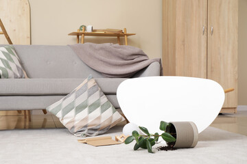 Overturned table and houseplant in living room after earthquake