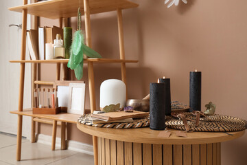 Witch's magic attributes with burning candles on table in room, closeup
