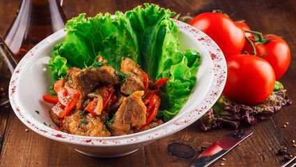 White plate holding beef stew garnished with lettuce on restaurant table