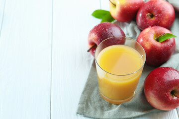 Refreshing apple juice in glass and fruits on white wooden table, closeup. Space for text
