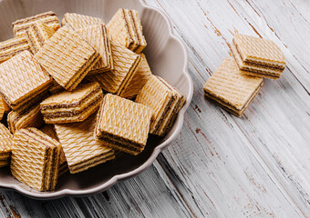 Delicious layered wafers arranged in a bowl on a wooden table