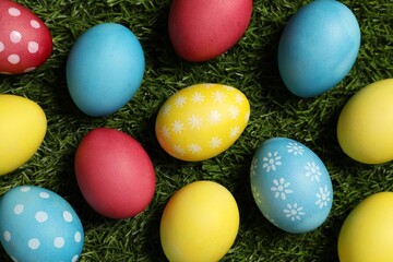 Beautiful decorated Easter eggs on green grass, flat lay