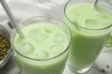 Fresh mung bean juice in glasses and seeds on table, closeup