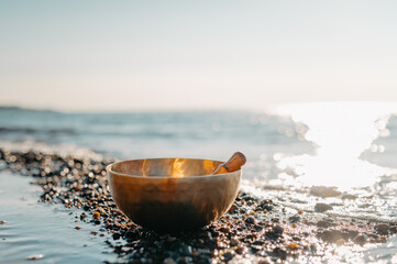 Tibetan Singing Bowl on a Rocky Beach with Ocean Waves at Sunset