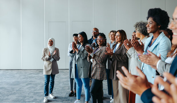 Diverse conference crowd clapping and smiling in a meeting room