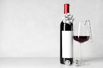 Bottle and glass of wine with Christmas candy cane on white grunge background