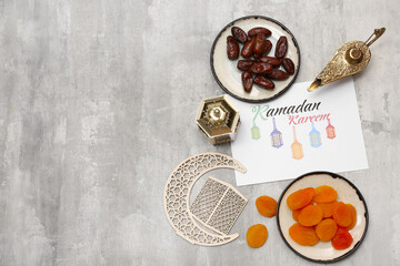 Greeting card, Aladdin lamp, dried apricots and dates on grey grunge background. Ramadan celebration