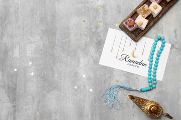 Greeting card, prayer beads, Turkish delight and Aladdin lamp on grey grunge background. Ramadan...