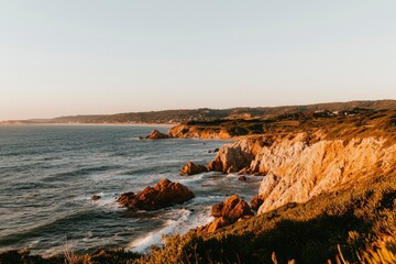 Obraz premium Golden Sunset Coastline with Cliffs and Ocean Waves