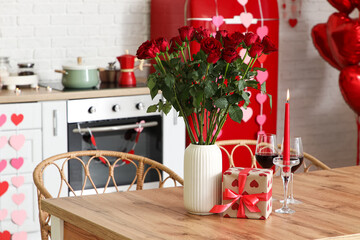 Table with wine, roses and gift box in festive kitchen. Valentine's Day celebration