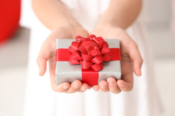 Cute little happy girl with gift box at home, closeup. Valentine's Day celebration