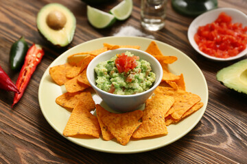 Plate with traditional Mexican nachos and guacamole on wooden background. Cinco de Mayo (Fifth of May) celebration