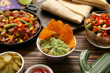 Bowl with Traditional Mexican guacamole and nachos on wooden background, closeup. Cinco de Mayo (Fifth of May) celebration