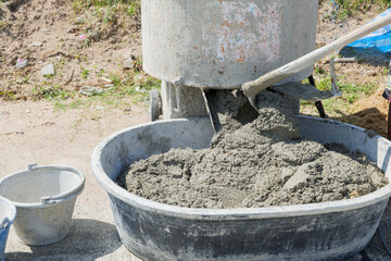 A cement mixer blending gray mortar with tan sand, its blades ensuring a uniform concrete mix.