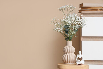 Vase with gypsophila flowers on coffee table near chest of drawers in room. Closeup