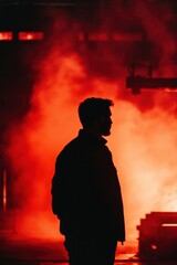 Man Silhouetted Against Red Smoke in Industrial Setting