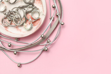 Tray with beautiful silver jewelry on pink background