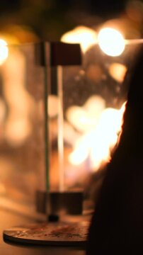 Serata romantica, la mano sul calice di un Cocktail e il calore del fuoco delle luci e del fuoco sullo sfondo.
Un Cocktail servito in una location piena di luci e di emozione.