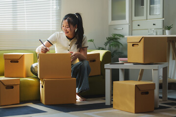 Young woman labelling cardboard boxes while moving home