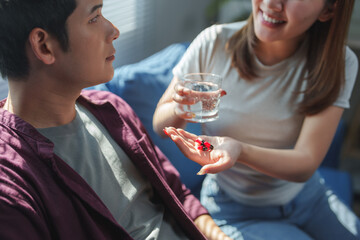 Woman giving medication and water to her sick partner at home