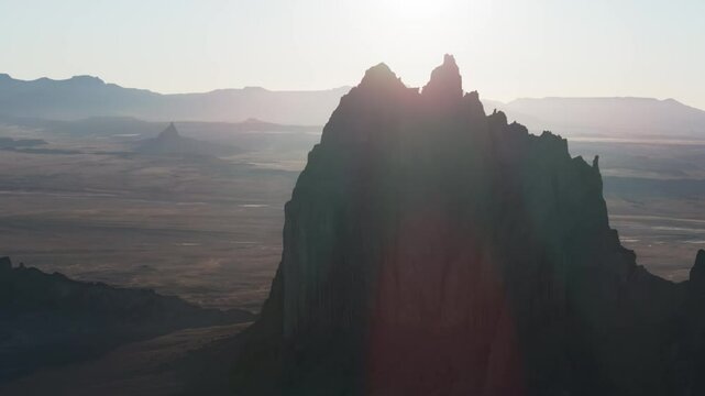 An unworldly, high-contrasted aerial shot of the sacred &ldquo;Ship Rock&rdquo;, a massive, monolithic rock butte, towering above the high desert plain of the Navajo Nation, in New Mexico, as the sun sets behind.