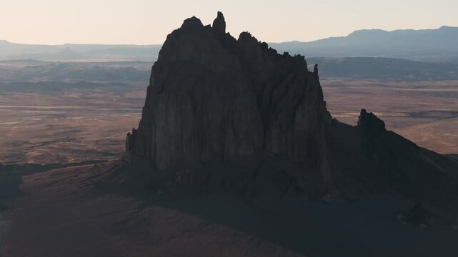 An unworldly, slow- rising 70mm aerial shot of the sacred &ldquo;Ship Rock&rdquo;, a massive, monolithic rock butte, towering above the high desert plain of the Navajo Nation, in New Mexico.
